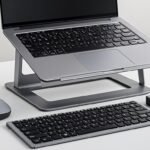 Laptop accessories every blogger needs including USB hub, wireless mouse, laptop stand, and external keyboard on a clean desk